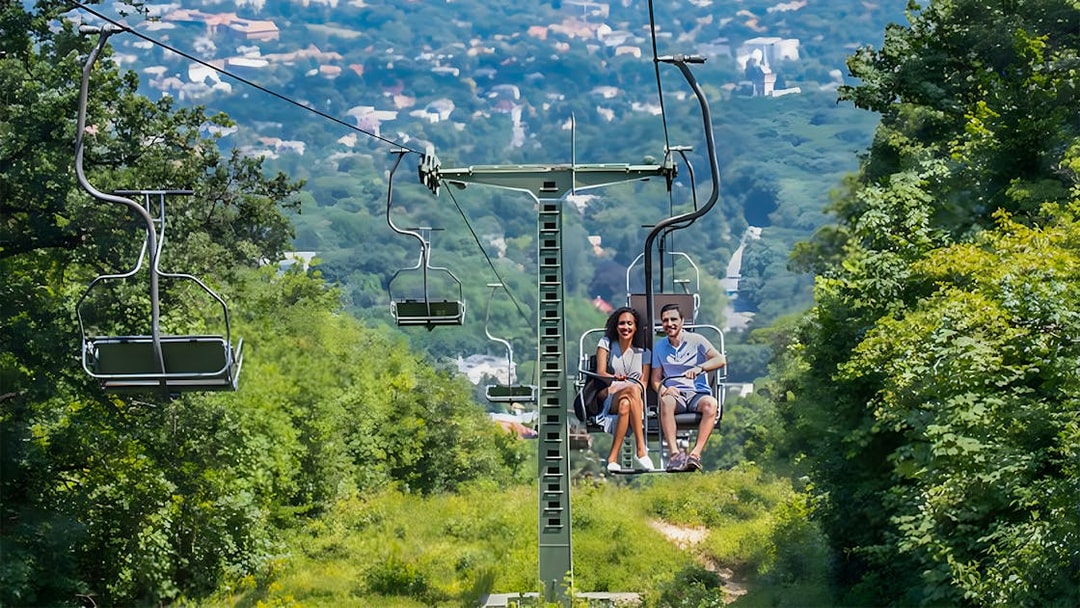 Gondola lift with passengers overlooking Budapest cityscape.