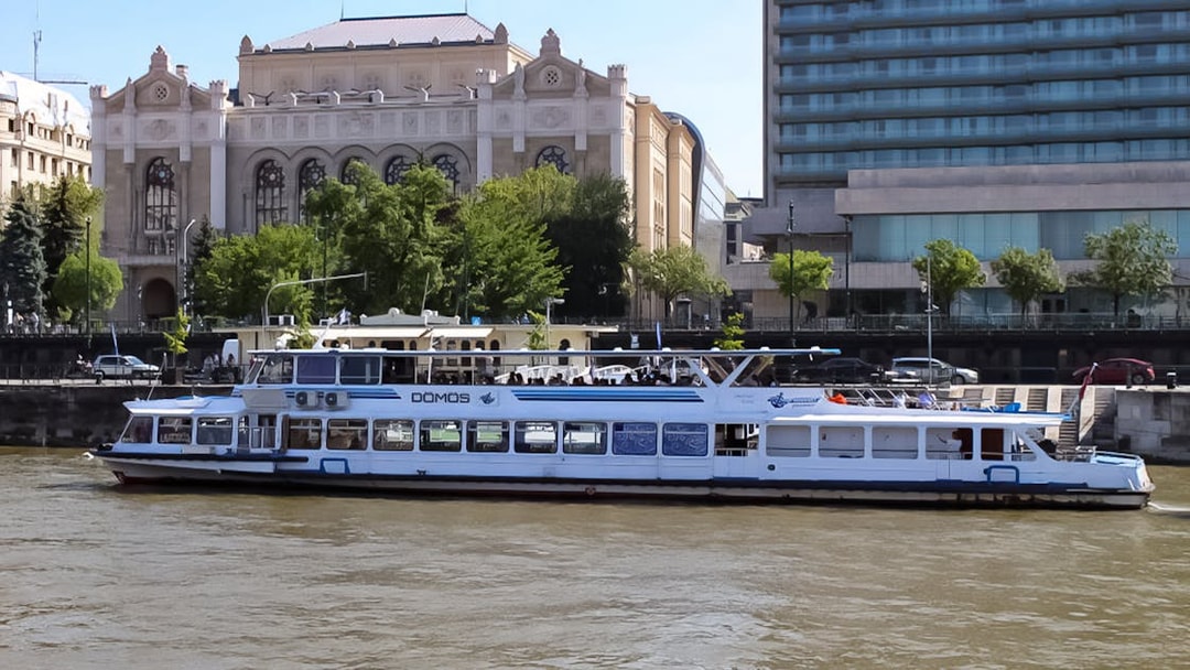 Danube River cruise boat passing historic building in Budapest.