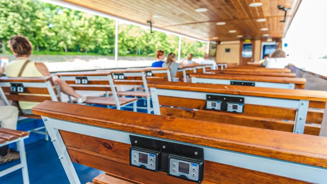 Passengers seated on a Danube River cruise boat with audio guide devices.