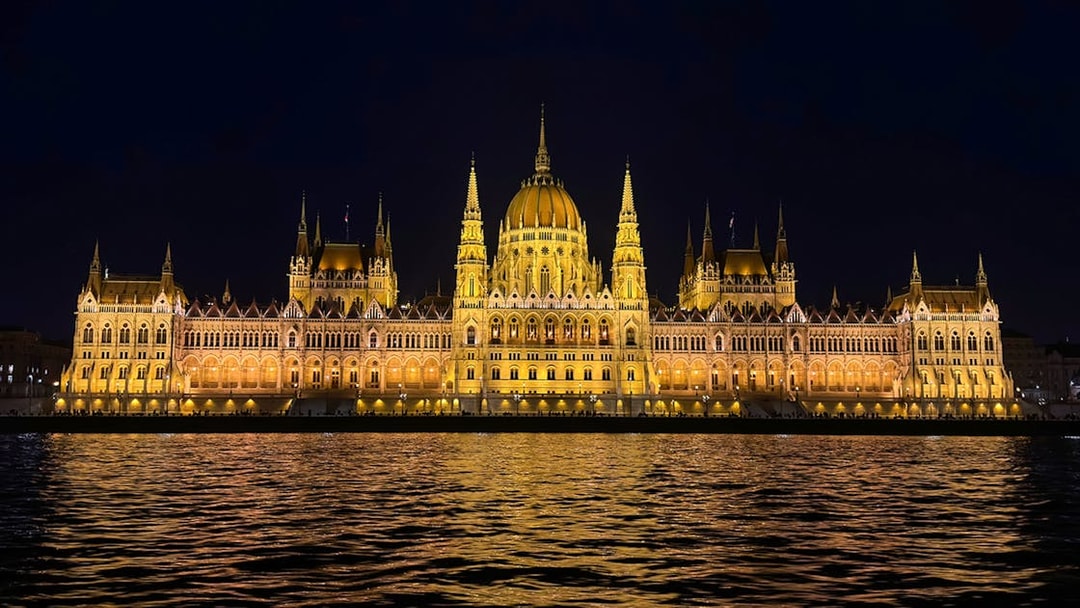 Hungarian Parliament Building illuminated at night, viewed from the Danube River.