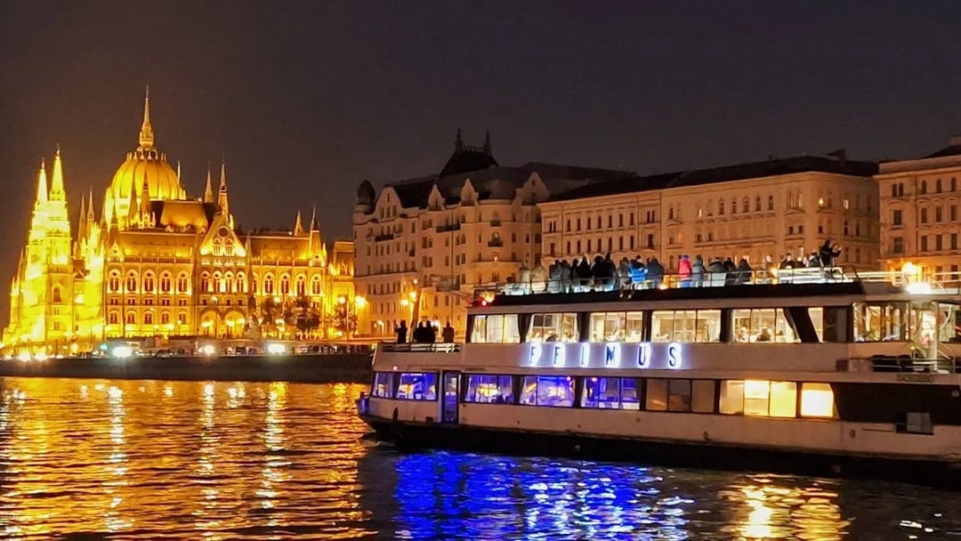 Dinner cruise on the Danube River with Budapest Parliament illuminated at night.