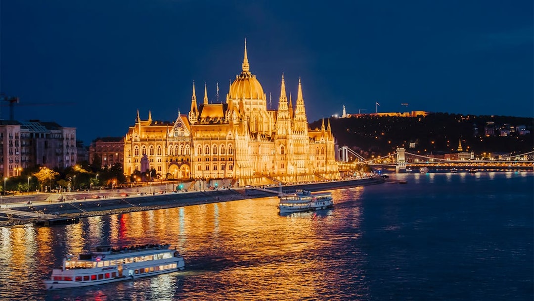 Nighttime cruise on the Danube River by the illuminated Hungarian Parliament in Budapest.