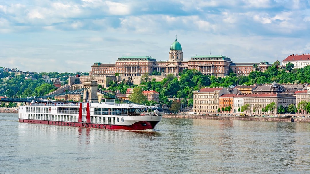 Cruise ship on the Danube River with Buda Castle in Budapest.