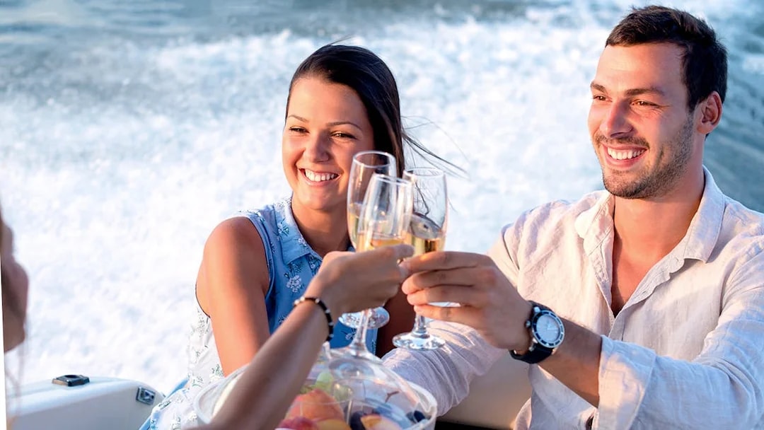 Guests toasting on a Santorini catamaran cruise with fruit platter.
