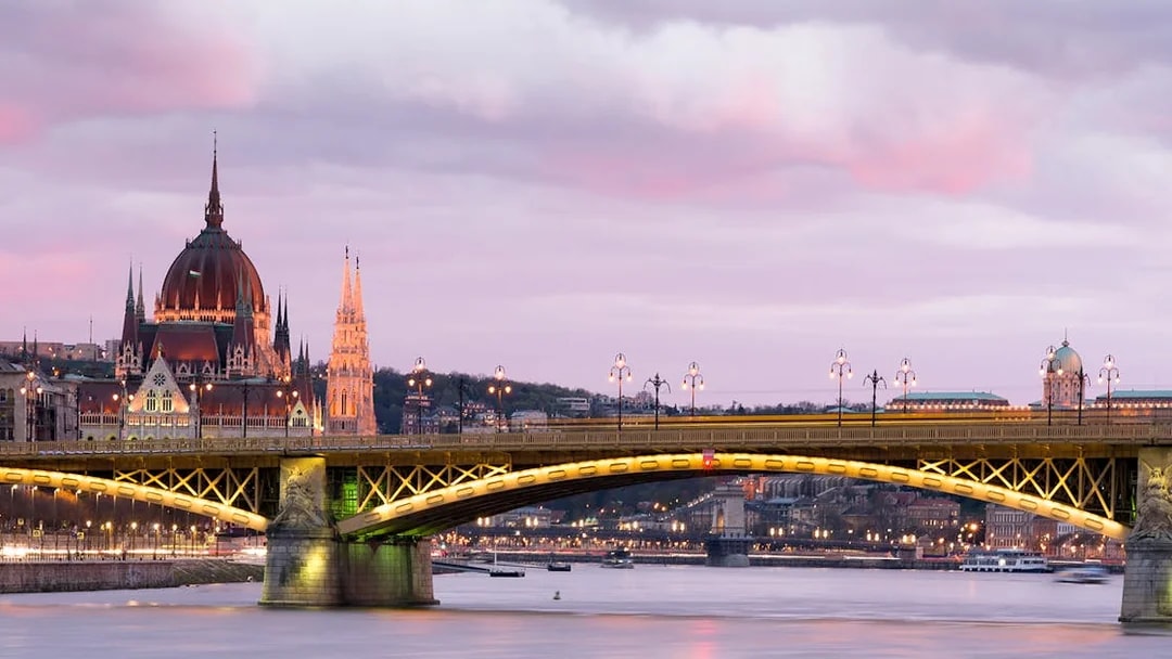 Parliament building and bridge over Danube River at sunset in Budapest.