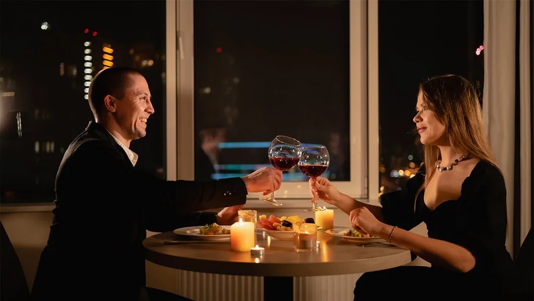 Couple toasting wine glasses during candlelight dinner on Budapest Danube River cruise.
