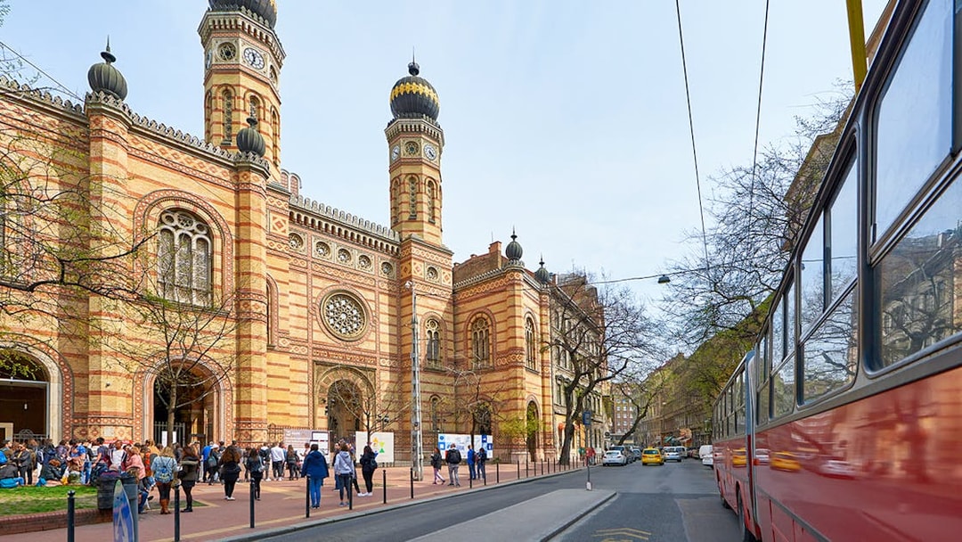 Central Synagogue of Budapest with visitors and a tram passing by.