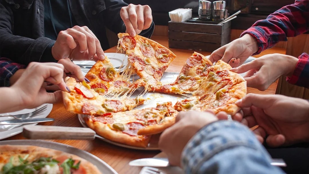 People sharing a pepperoni pizza at a restaurant in West End.