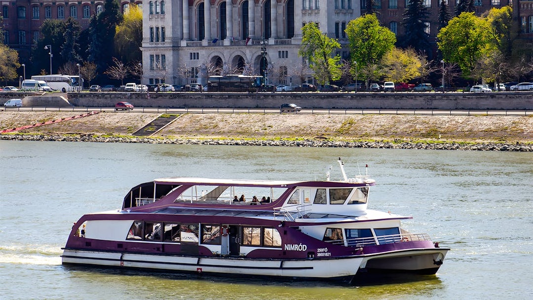 Danube cruise boat with passengers near Budapest riverside.