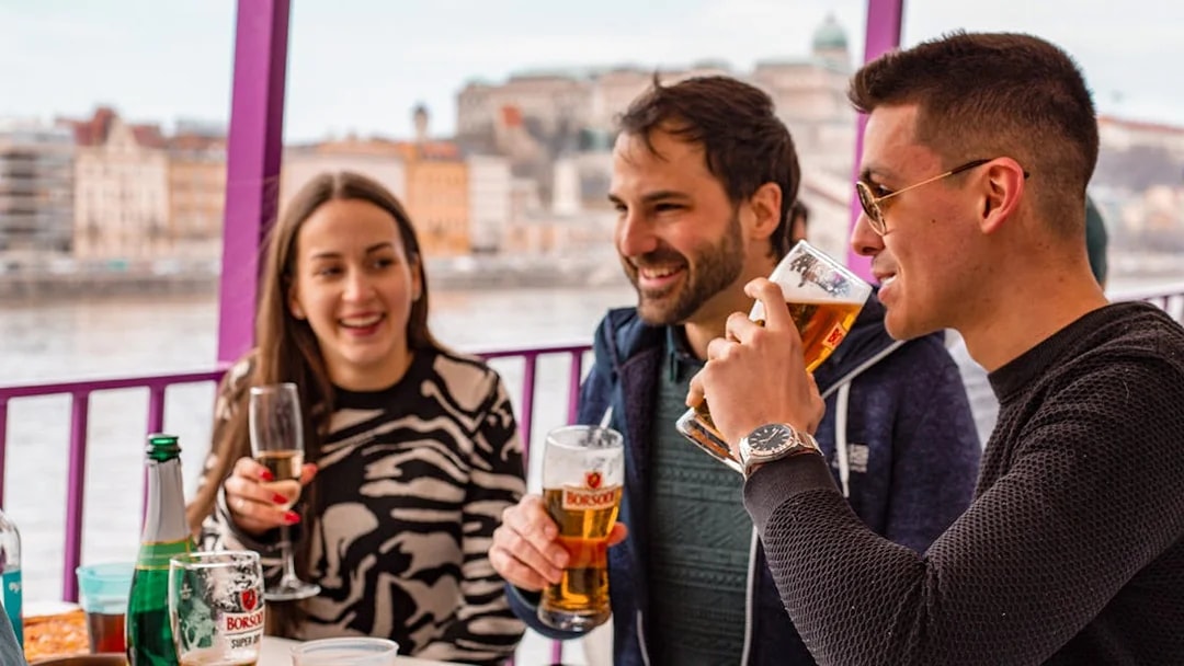 Group enjoying drinks and pizza on a Budapest party boat cruise.