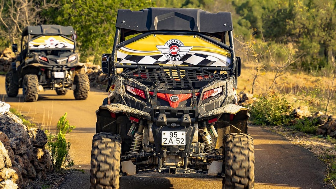 Buggy driving on a dirt path during Algarve tour, surrounded by greenery.