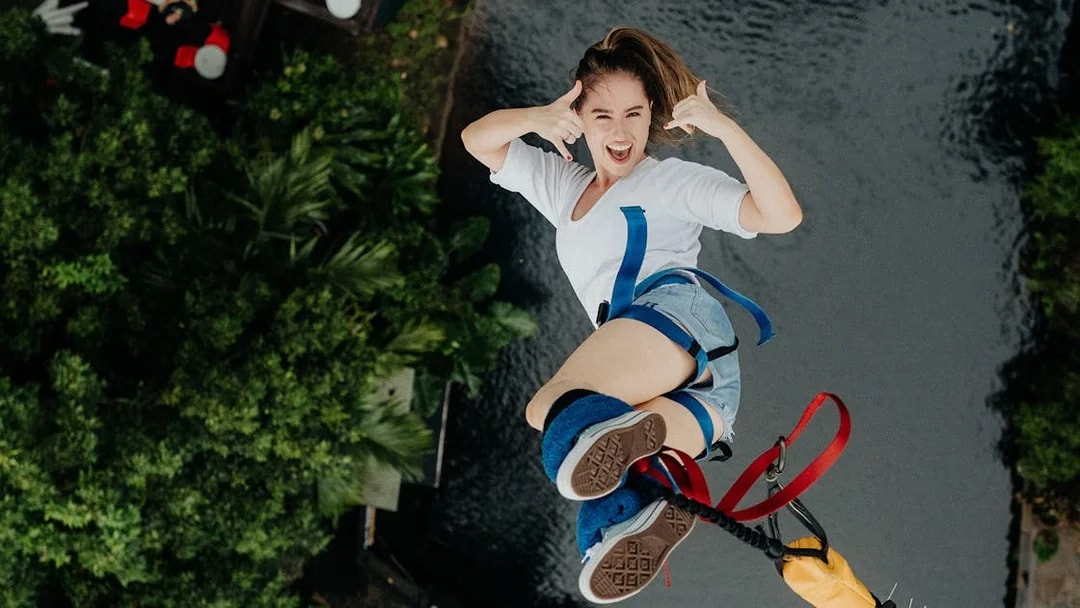 Person bungy jumping over lush greenery and water in Cairns, Australia.