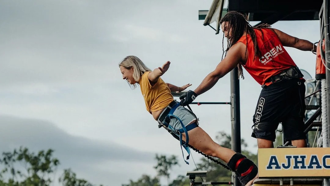 Person bungy jumping from platform in Cairns, Australia, assisted by crew member.