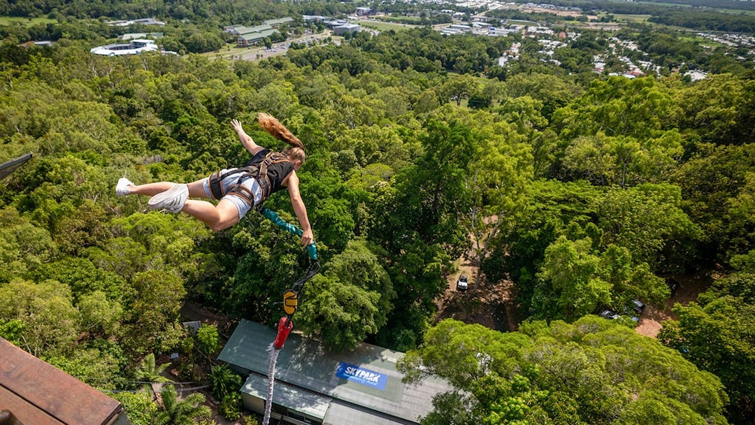 Person bungy jumping over lush forest in Cairns, Australia.