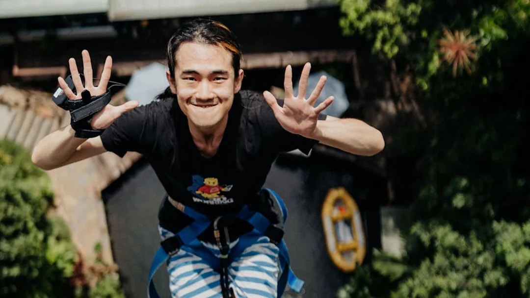 Person mid-air during a bungy jump in Cairns, Australia, with lush greenery below.
