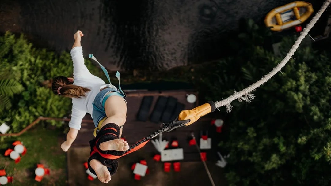 Person bungy jumping over lush greenery in Cairns, Australia.