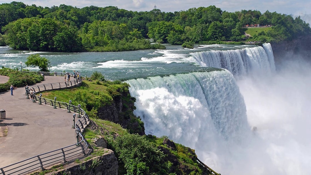 Visitors at Niagara Falls viewpoint overlooking the waterfall and river.
