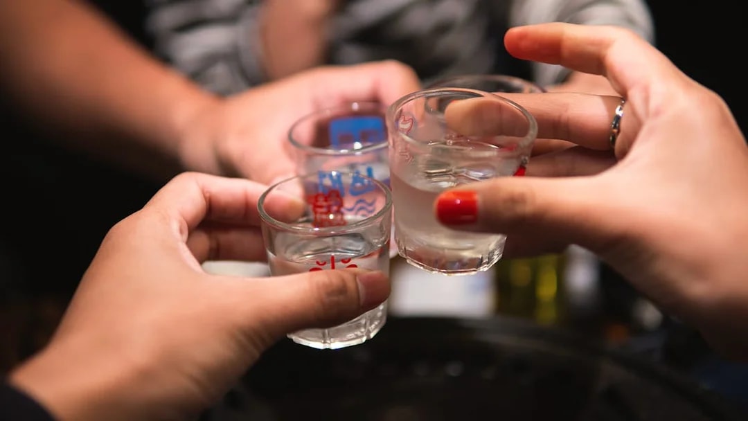 People toasting with shot glasses during Busan pub crawl.
