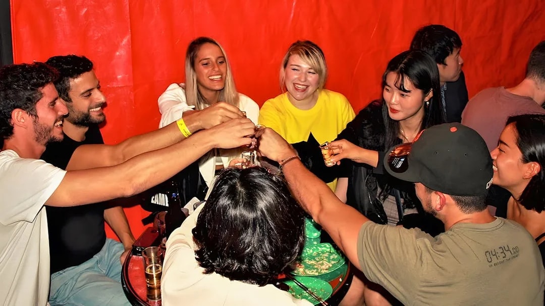 Group enjoying drinks at a Busan pub crawl, raising glasses in a lively atmosphere.