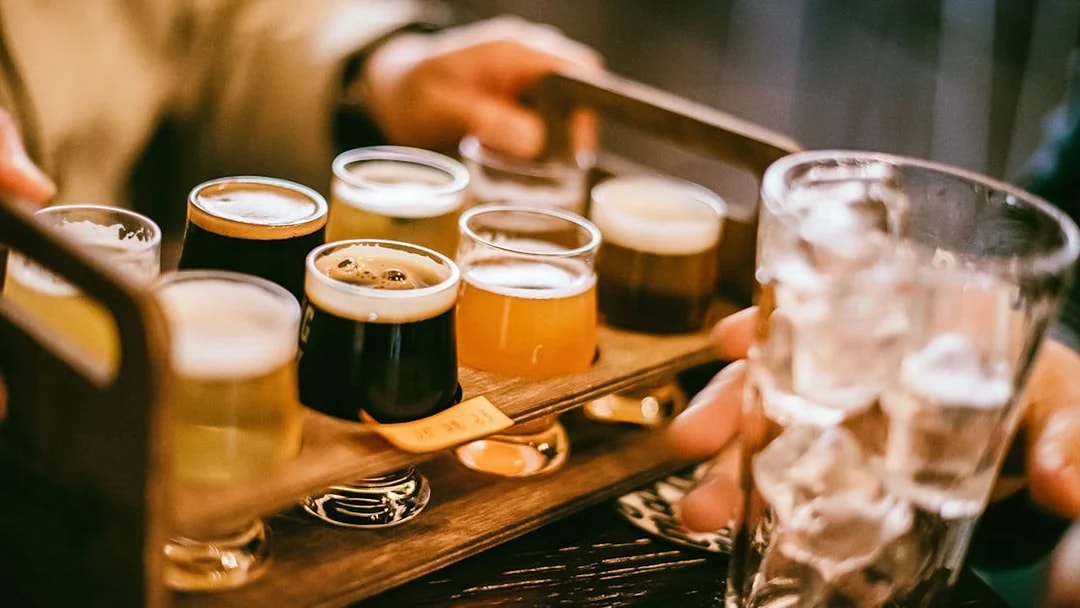 Flight of craft beers on a wooden tray during Busan pub crawl.