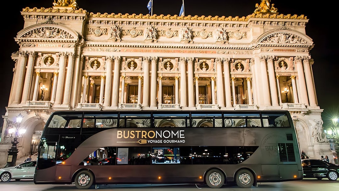 Bustronome Paris bus in front of Opera Garnier at night.