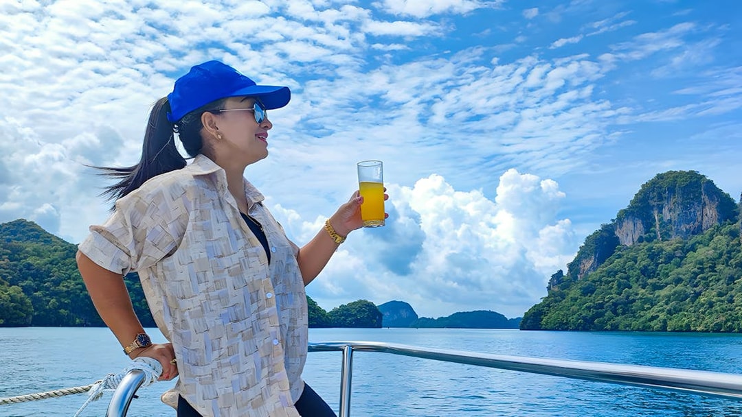 Woman enjoying juice on a lunch cruise with scenic ocean and island views.