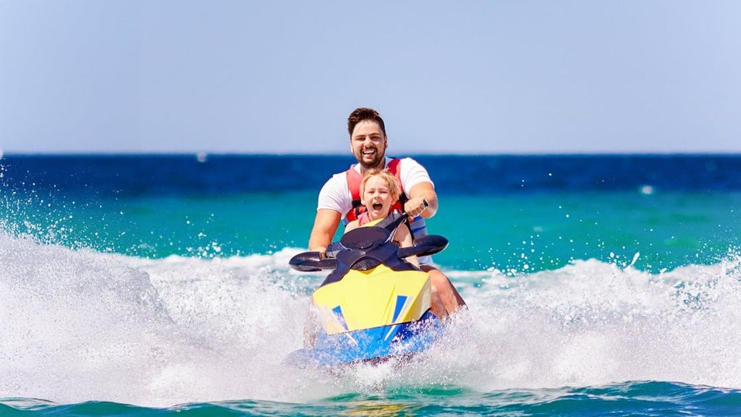 Father and son riding a jetski on Langkawi island hopping tour.