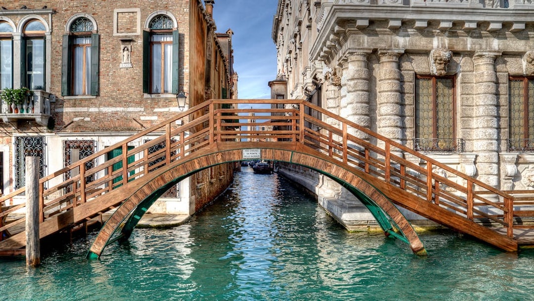 Wooden bridge over canal between historic buildings in Venice near Ca' Rezzonico.