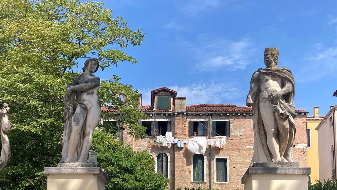 Statues in Ca' Rezzonico Gardens with historic building, Venice.