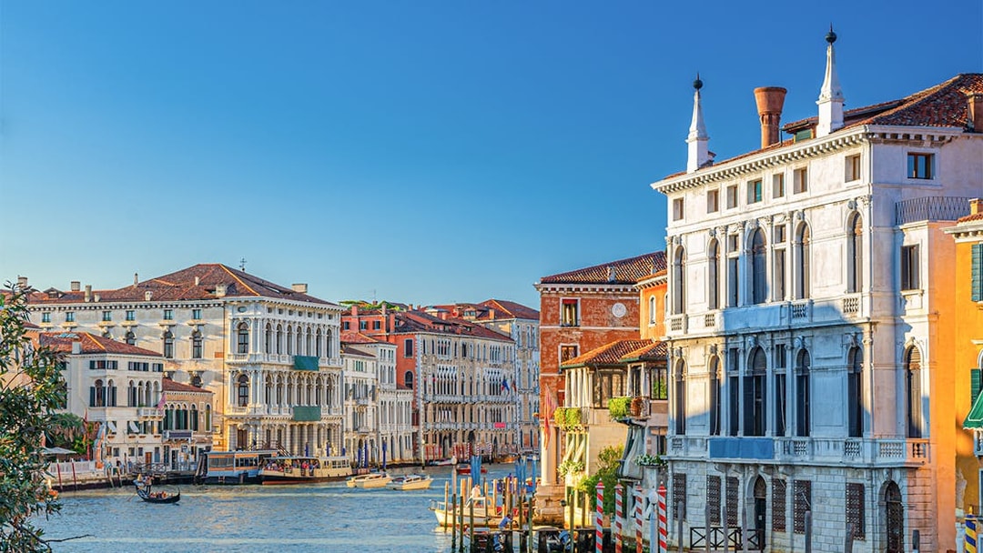 Ca' Rezzonico along the Grand Canal in Venice with gondolas and historic buildings.