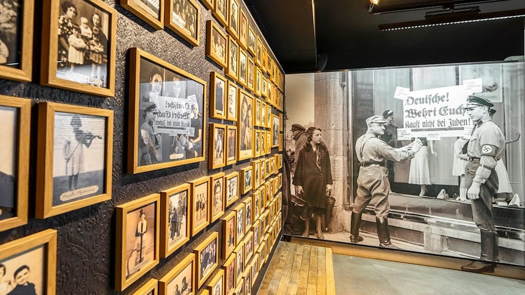 Wall of historical photos at Caen Memorial Museum, depicting World War II events and Nazi propaganda.
