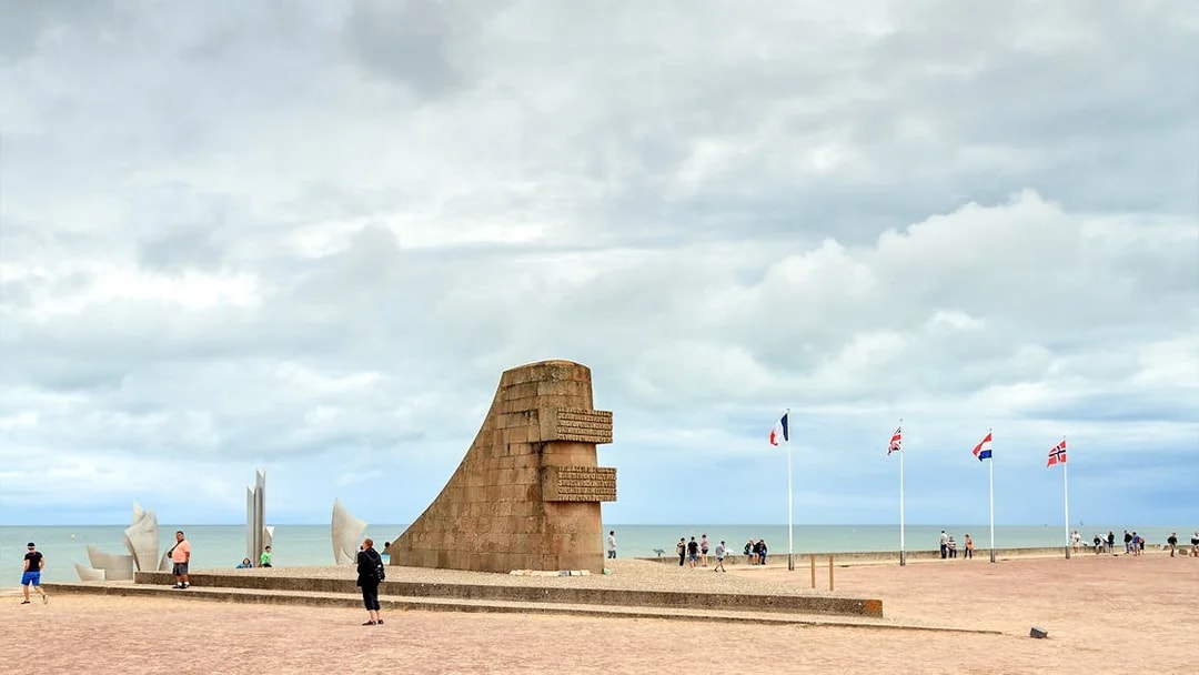 Omaha Beach monument with international flags, Normandy coast, related to D-Day landings.