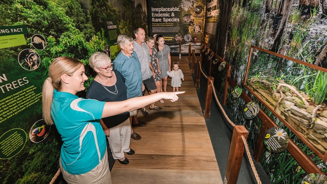 Visitors touring Cairns Aquarium exhibit with guide pointing at display.