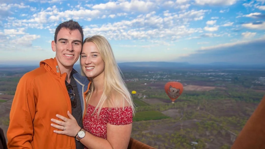 Couple enjoying a hot air balloon ride over Cairns with scenic landscape views.
