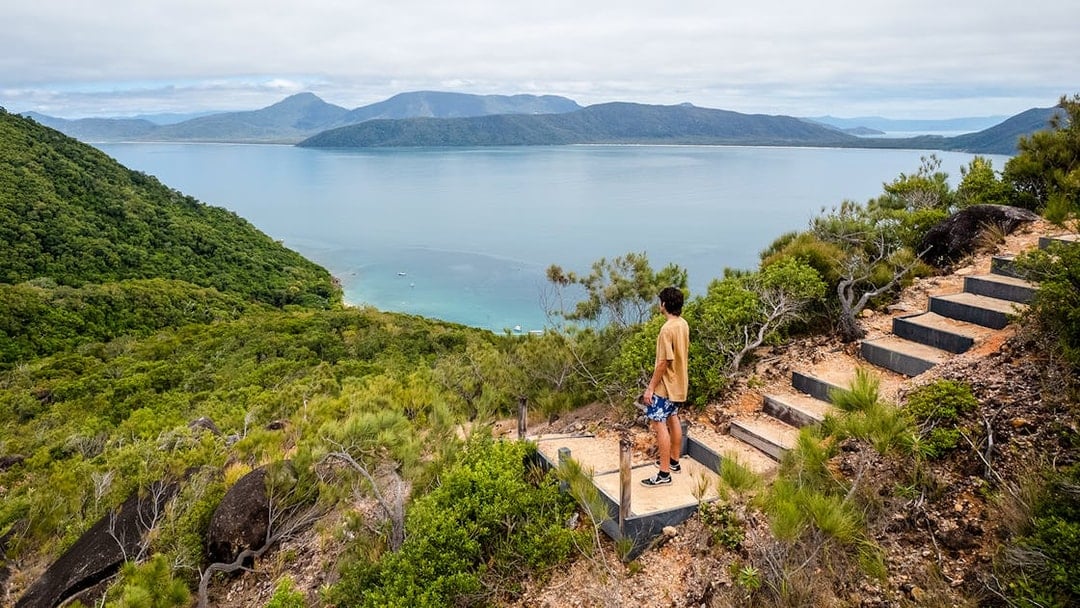 Person overlooking ocean and lush hills on Fitzroy Island adventure trail.