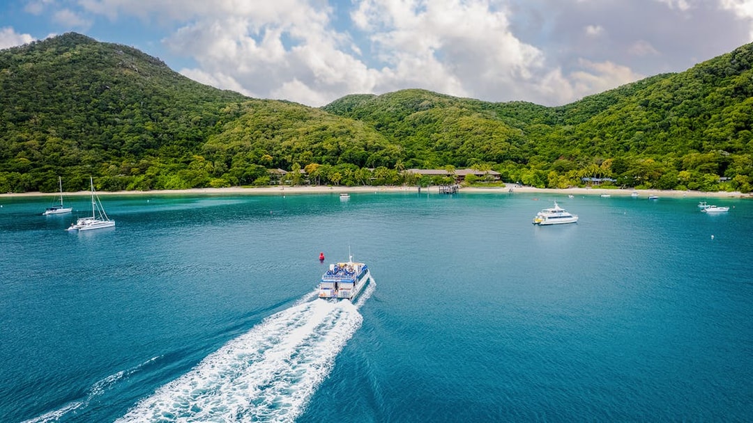 Boat approaching Fitzroy Island with lush hills and clear blue water.