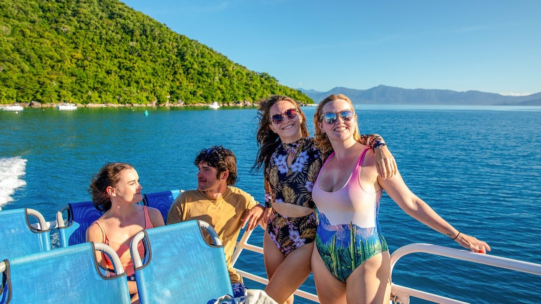 Group enjoying a boat ride from Cairns to Fitzroy Island with lush hills and ocean views.