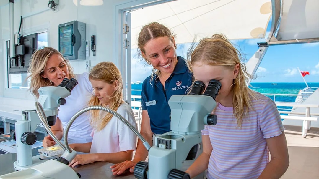 Marine biologists and children using microscopes on a Great Barrier Reef cruise from Cairns.