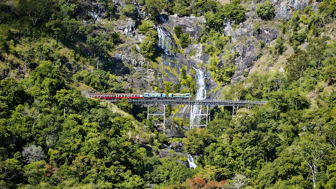 Kuranda Scenic Railway crossing Stoney Creek Falls in lush rainforest.