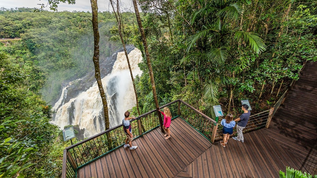 Visitors at a Kuranda lookout point viewing a waterfall amidst lush rainforest.