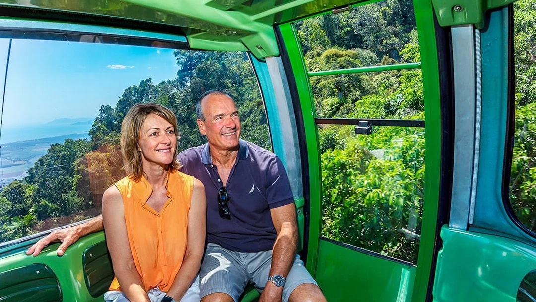 Couple enjoying the view from Kuranda Skyrail Cableway over lush rainforest and coastline.