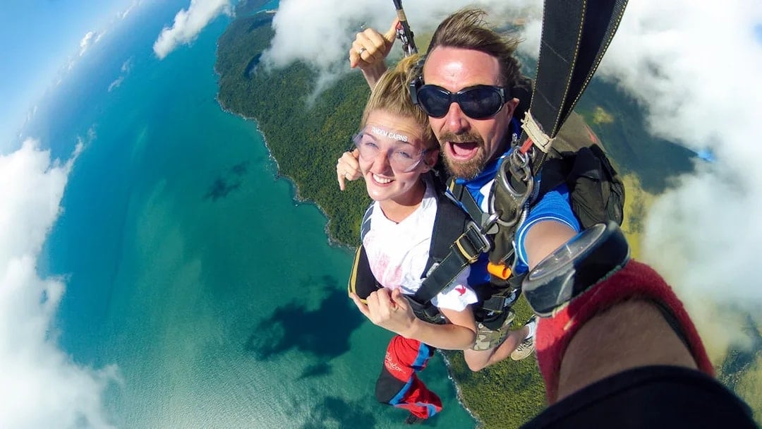 Tandem skydive over Cairns coastline with ocean and forest views.
