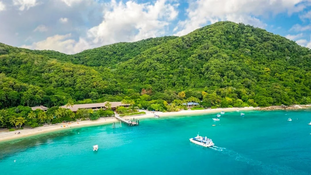 Boats near the shore of Fitzroy Island with lush green hills in the background.