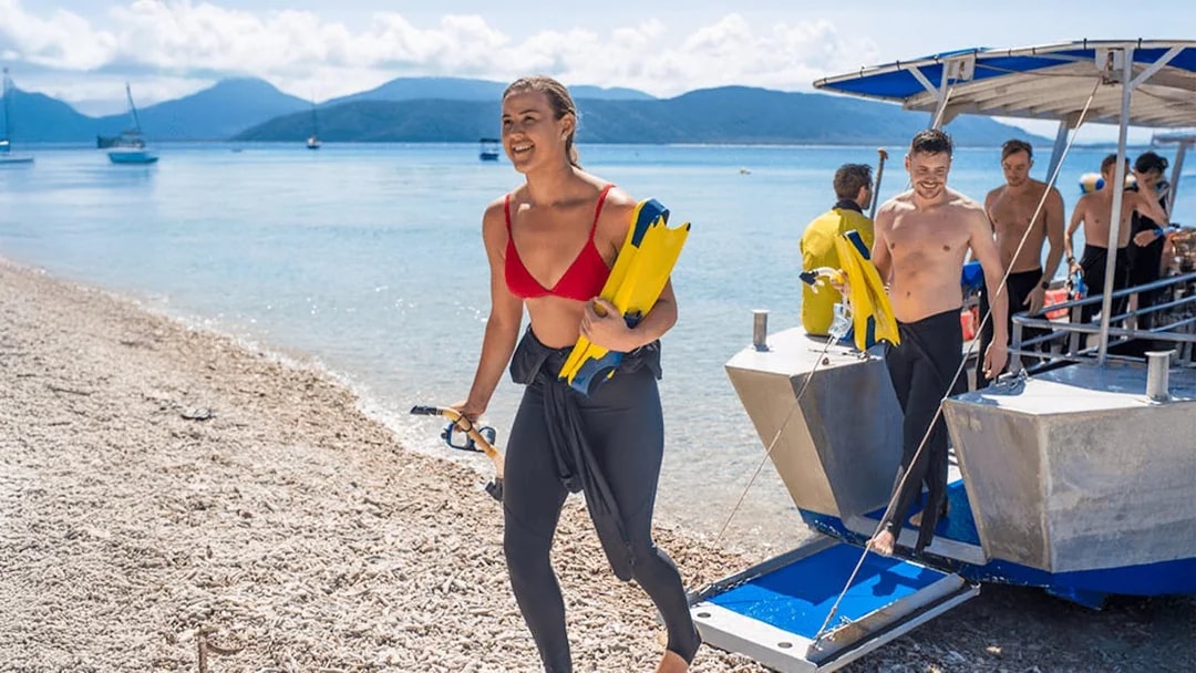 Tourists disembarking from a boat after snorkeling at Fitzroy Island beach.