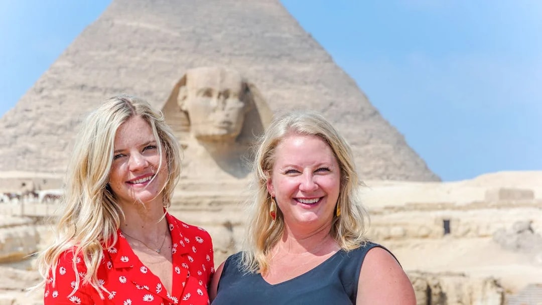 Tourists smiling in front of the Sphinx and Pyramid in Giza, Egypt.