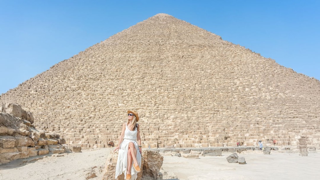 Tourist sitting on rock in front of Giza Pyramid, Egypt.