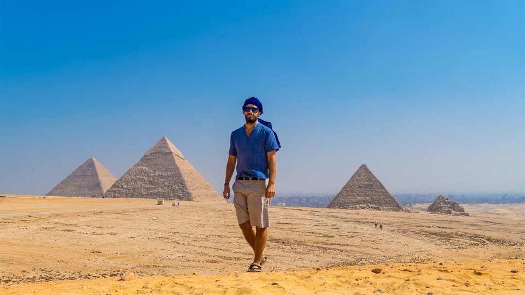 Man walking near the Pyramids of Giza, Egypt, under a clear blue sky.