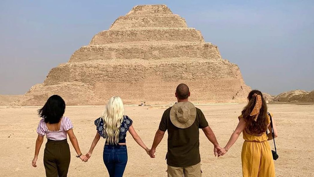 Tourists holding hands in front of the Step Pyramid at Saqqara, Egypt.