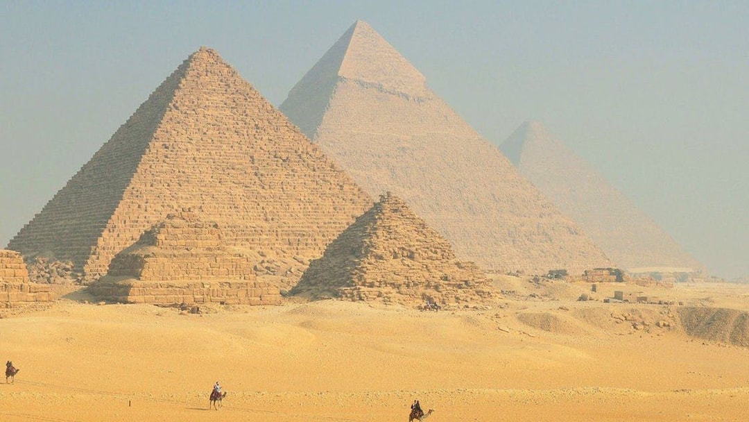 Pyramids of Giza with camels in the foreground, Egypt desert landscape.