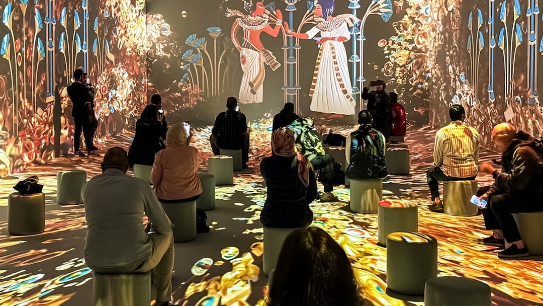 Visitors seated, watching an interactive digital exhibition with ancient Egyptian themes.